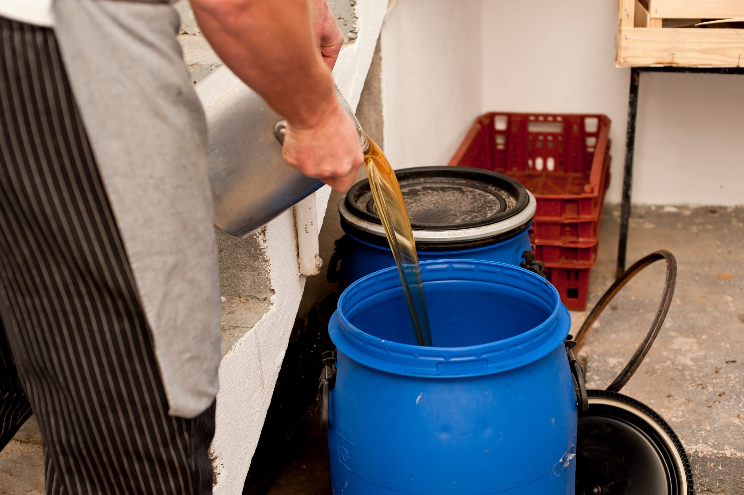 Used cooking oil collection in blue plastic open-top drum for recycling