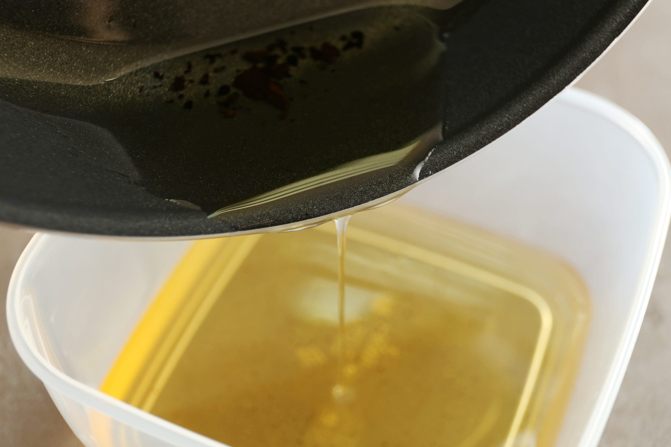 Used cooking oil being poured from pan into container for recycling - Wastecare